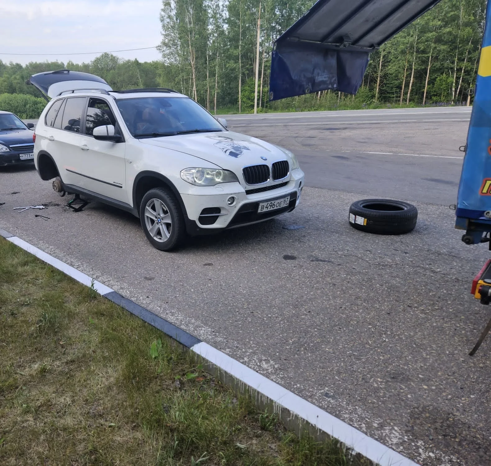 Выездной шиномонтаж автомобиля BMW BMW со снятым задним колесом рядом с мобильной мастерской Протектор